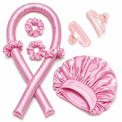 Pink satin heatless curl kit with rod, scrunchies, clips and bonnet on white background