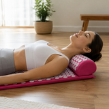 Person relaxing on the rose-pink acupressure mat with the neck pillow