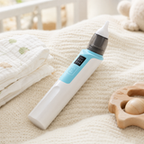 Baby nasal aspirator resting on a soft knit blanket with nursery props