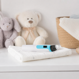 Baby nasal aspirator resting on a folded blanket in a soft nursery setting