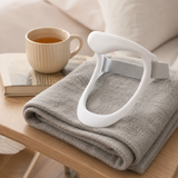 Cervical neck support brace resting on a folded blanket with tea, calm home wellness scene