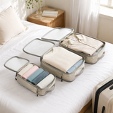 Compression packing cubes filled with folded clothes on a sunlit bed, ready for travel