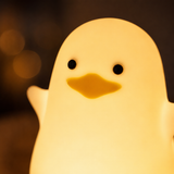 Close-up of the silicone duck night light glowing face with black dot eyes and yellow beak