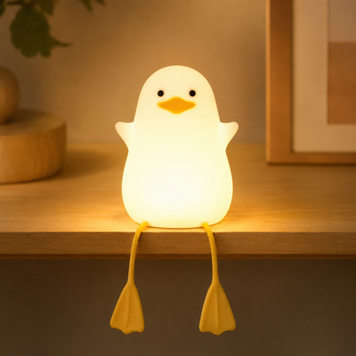 Glowing white silicone duck night light with dangling yellow feet on a shelf