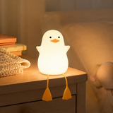 Duck silicone night light glowing warmly on a nightstand in a cozy bedroom