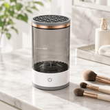 Electric makeup brush cleaner on a bright marble bathroom vanity with makeup brushes