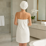 Woman seen from behind wearing the cream microfiber bath wrap and hair turban in a bright bathroom