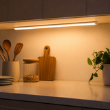 Motion-sensor LED light bar mounted under a kitchen cabinet illuminating the counter