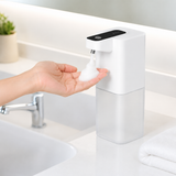 Touchless soap dispenser dispensing foam onto a hand at a clean bathroom sink